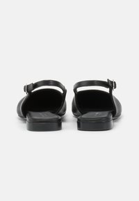 Sandales noires en cuir avec un dos ouvert, une fine sangle de cheville et un petit talon carré. Texture lisse avec un design minimaliste.