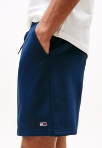 Marineblaue Shorts aus weichem Stoff, mit Seitentaschen und einem kleinen Logopatch. Elastischer Bund mit Kordelzug für eine verstellbare Passform.