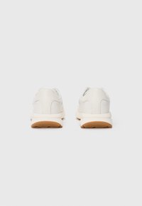 Vita sneakers med slät läderöverdel, rund tå och mjuk gummisula. Designade med diskret sömnad och en liten logotyp vid hälen.