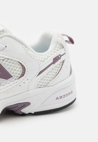 Tenis sportivi albi cu detalii din plasă și piele, accente violet, talpă cu amortizare și branding "ABZORB" pe călcâi.