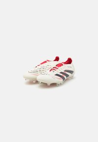 White soccer cleats with red and black accents, textured surfaces, and a streamlined design. Features a lace-up closure and molded studs.