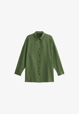 Chemise verte à manches longues, en tissu texturé. Dotée d'un col et de coutures verticales le long de l'avant.