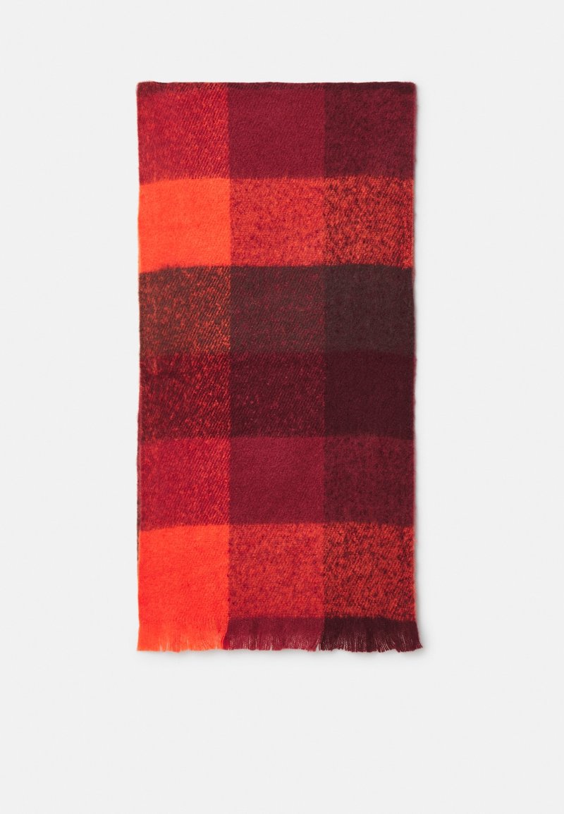 Écharpe rectangulaire en laine avec un grand motif à carreaux rouges et oranges et des franges courtes sur une extrémité, présentée à plat sur un fond blanc.