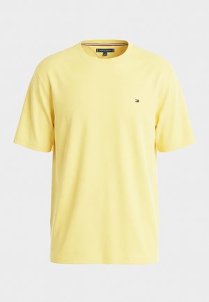 Tricou galben din bumbac cu mâneci scurte, gât rotund și logo mic Tommy Hilfiger pe pieptul stâng, pe fundal alb.