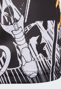 Czarna tkanina z wyraźnym białym i żółtym wzorem graficznym, z napisem „AEROREADY”, o gładkiej, sportowej fakturze.