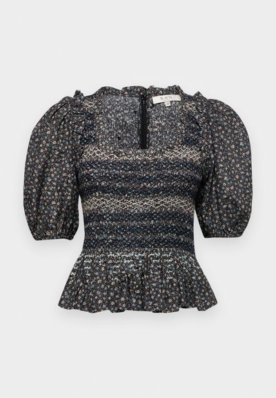 Musta kukallinen paita, jossa on puffihihat, karkea yläosa ja röyhelöhelma. Takana on vetoketjukiinnitys ja tekstuuriaines.