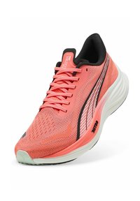Zapatilla de running de malla color coral con acentos negros, diseño elegante, superficie texturizada, franjas reflectantes y suela blanca acolchada.