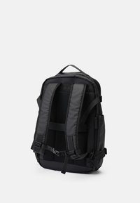 Mochila negra hecha de un tejido durable, con correas de hombro de malla acolchada, hebillas ajustables y múltiples compartimentos para almacenamiento.