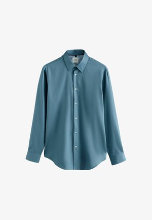 Türkiz színű, hosszúujjú, gombos ing, hegyes gallérral és fehér gombokkal, szépen összehajtva egy fehér háttér előtt.