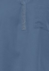 Chemise bleue à manches courtes avec un léger éclat, patte de boutonnage et poche sur le côté gauche de la poitrine. Fabriquée en tissu léger et lisse.