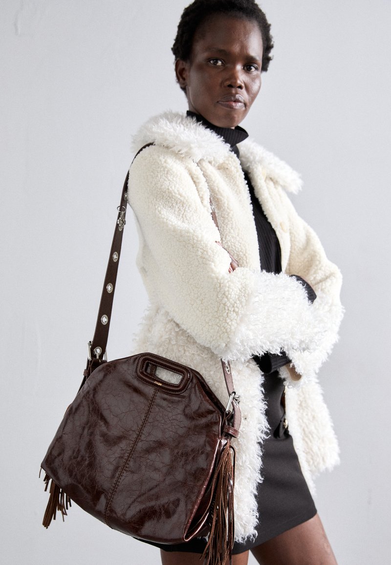 Brown leather handbag with a textured finish, pleated edges, and side tassels; features a detachable shoulder strap with metal accents.