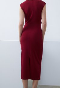 Vestido midi burdeos con una silueta ajustada, mangas de golpe y una abertura en la parte posterior para mayor comodidad. Tejido suave con un acabado mate.