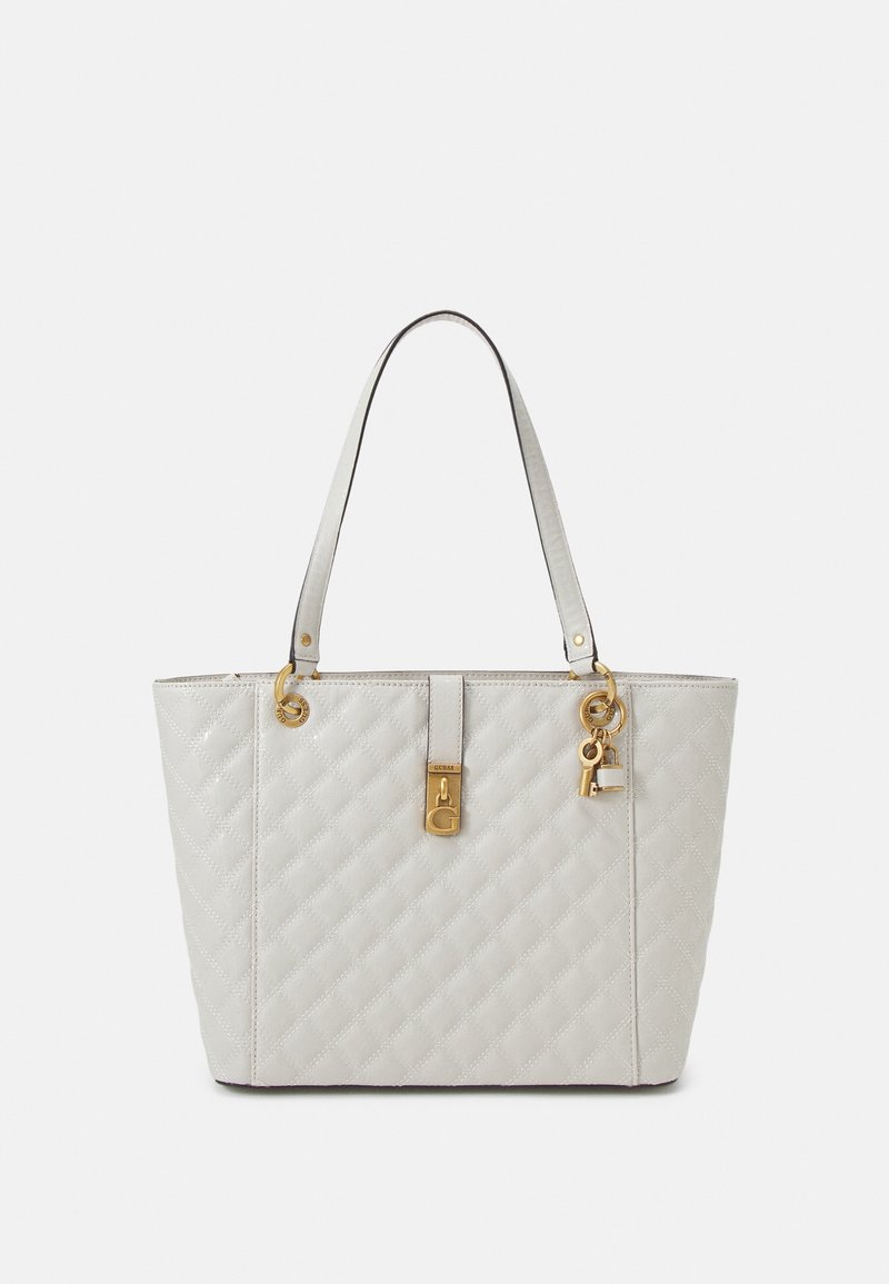 Sac cabas en cuir blanc matelassé avec double poignée, détail de serrure dorée et petits charms représentant une clé et un cadenas suspendus.