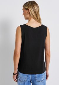 Musta hihaton paita, jossa on pyöreä kaula-aukko, valmistettu pehmeästä materiaalista. Ominaisuuksiin kuuluu sileä pinta, rento mitoitus ja se ulottuu juuri vyötärön alapuolelle.