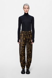 Μαύρο μπλουζάκι με μακριά μανίκια και ριχτό λαιμό, συνδυασμένο με φαρδιά παντελόνια σε καφέ και μαύρο tie-dye σχέδιο και μαύρα μποτάκια αστραγάλου. Ομαλή υφή με σούρα στη μέση.