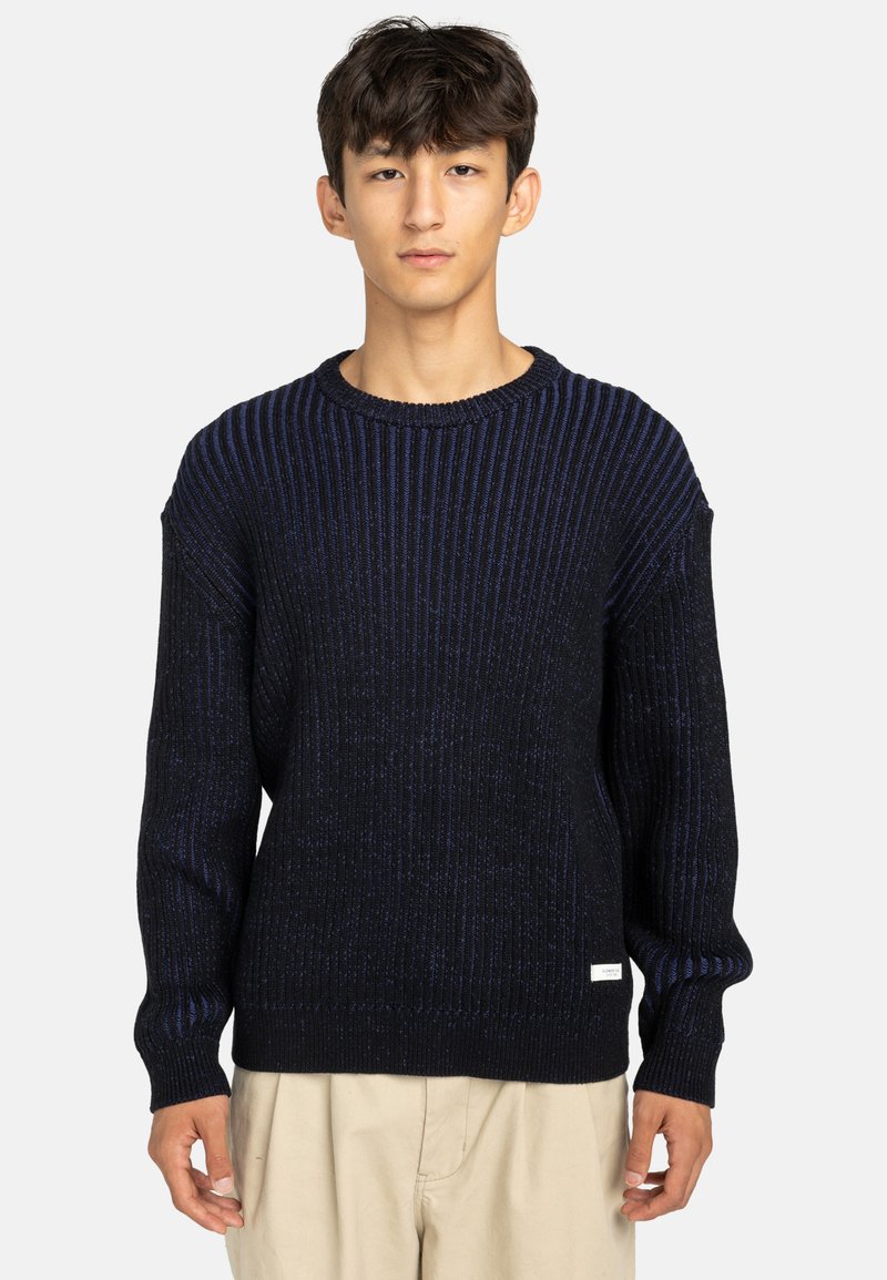 Maglione a maglia blu navy con strisce verticali blu, collo rotondo e texture a costine. Presenta un piccolo etichetta sull'orlo sinistro.