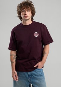 Maroon cotton t-shirt with short sleeves and a round neckline. Front left chest features "NEW YORK RECORDS" in white and pink text.