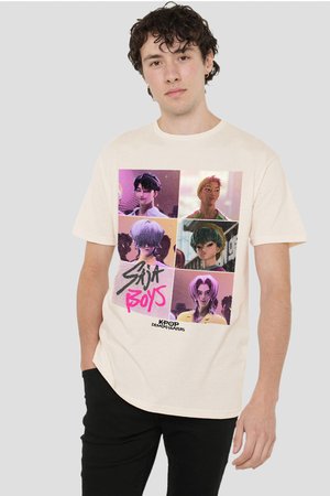 Junger Mann mit lockigem Haar, der ein helles T-Shirt trägt, auf dem sechs animierte Charakterporträts und der Text "Sky Boys K-Pop Demon Hunters" abgebildet sind.