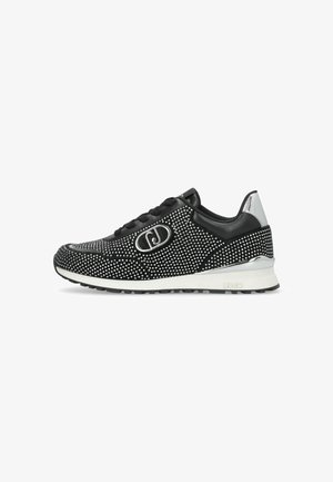 Baskets noires montantes basses avec des clous en argent, détail métallisé au talon, semelle blanche, lacets noirs et un logo circulaire en argent sur le côté.