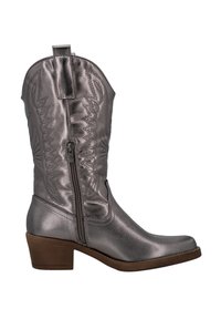 Bota vaquera metálica plateada con costuras decorativas, cremallera lateral, punta afilada y un tacón marrón apilado. Textura de cuero suave en todo.