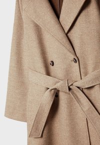 Karmelowy, podwójnie zapięty płaszcz wykonany z teksturowanej mieszanki wełny, z dużymi brązowymi guzikami i paskiem do przewiązania w talii.