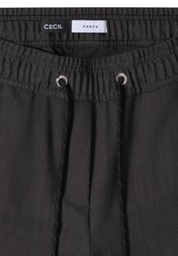 Donkergrijze broek met elastische tailleband, zwarte trekkoorden met metalen oogjes en een label met "CECIL BROEK" binnenin de tailleband.