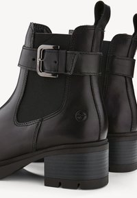 Stivaletti neri in pelle con pannello elastico, dettaglio con fibbia e tacco spesso e texturizzato per stabilità. Logo discreto sul lato.