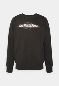 Svart sweatshirt med rundad halsringning, långa ärmar och en stor grafisk logotyp "The North Face" i vitt över framsidan.