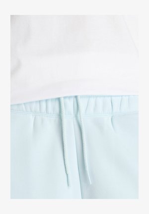 Pantaloni tuta azzurri con vita elasticizzata, cordino regolabile e texture morbida. Il tessuto appare liscio e leggero.