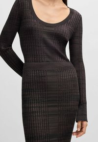 Neulemekko tumman purppuran ja mustan värisenä, jossa on ribbaaava tekstuuri. Varustettu pitkillä hihoilla ja leveällä pyöreällä kaula-aukolla. Muotoiltu siluetti kauttaaltaan.