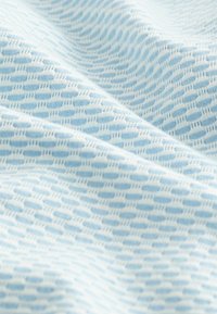 Vaaleansininen kangas, jossa on teksturoitu, kuvioitu pinta, jossa on pieniä soikeita muotoja ja hienoja yksityiskohtia, luoden visuaalisesti mielenkiintoisen tekstiilin.