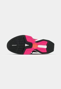 Semelle de chaussure de sport noire et rose avec une surface texturée, présentant un motif de semelle en caoutchouc prononcé et des formes géométriques de couleur rose vif.