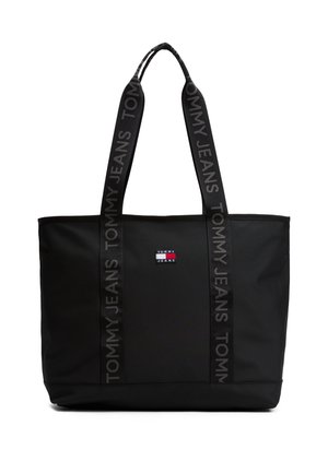 Sac cabas noir Tommy Jeans avec de larges anses, comportant un texte répété « Tommy Jeans » et un petit patch logo rouge, blanc et bleu au centre devant.