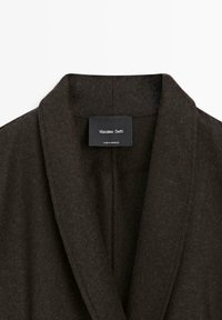 Tmavě hnědý kabát s šálovým límcem z vlněné směsi se štítkem zobrazujícím "Massimo Dutti." Má jemnou texturu a otevřený design vpředu.