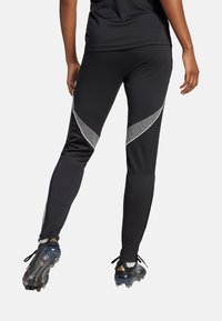Zwarte sportleggings met een taps toelopende vorm, voorzien van reflecterende zilveren accenten en een ontwerp met meshpanelen aan de zijkanten.
