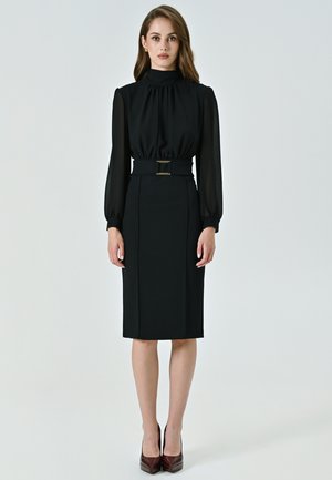 Schwarzes Kleid mit hochgeschlossenem Hals, langen transparenten Ärmeln und taillierter Silhouette. Verfügt über einen breiten Gürtel mit einer goldfarbenen Schnalle, knielanger Schnitt.