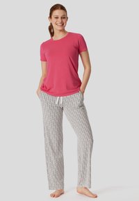 Camiseta de manga corta rosa combinada con pantalones de pijama blancos y grises, sueltos y con un diseño geométrico repetido.