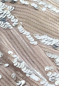 Tejido con lentejuelas con círculos plateados superpuestos sobre un fondo de encaje rosa claro, que presenta un patrón texturizado y una superficie brillante.