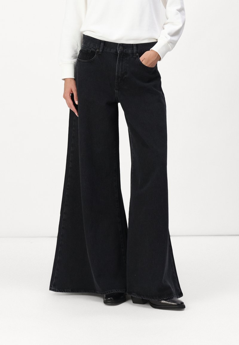 Zwarte wijduitlopende jeans van denim met een hoge taille, voorzien van zijzakken en een relaxte pasvorm, weergegeven met een witte top.