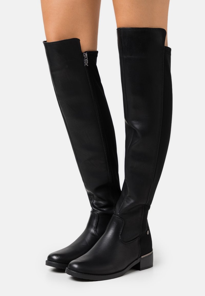 Bottes en cuir noires montant jusqu'aux genoux, avec une texture lisse, un bout arrondi et un petit talon bloc. Elles comportent une fermeture éclair latérale pour un enfilage facile.