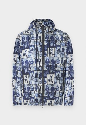 Ζακέτα με κουκούλα και φερμουάρ, με μπλε και λευκό κολάζ που απεικονίζει διάφορες ασπρόμαυρες φωτογραφίες ανθρώπων και αντικειμένων.