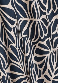 Tissu bleu marine avec une texture lisse présentant de grands motifs floraux crémeux stylisés et de vives bordures noires contrastées.