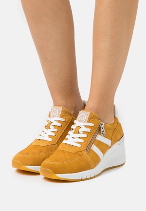 Baskets en suède jaune avec des rayures blanches et des lacets, dotées d'une fermeture éclair sur le côté et d'une semelle compensée pour plus de hauteur. Tige texturée pour une meilleure adhérence.