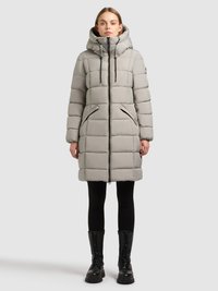 Harmaa toppatakki korkealla kauluksella, vetoketjullinen ja kahdella sivutaskulla varustettu. Siinä on suorakaiteen muotoinen malli, ja se on yhdistetty mustiin leggingsseihin ja saappaisiin.