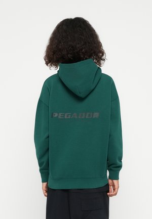 Green hoodie with a large "PEGADOR" printed in black on the back. Features a drawstring hood and ribbed cuffs. Smooth texture.