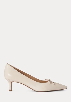 Béžové kožené lodičky s ostrou špičkou, malým mašlovým detailem na horní straně, nízkým tenkým podpatkem a hladkým povrchem.
