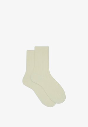 Calze color crema a coste, realizzate in materiale morbido, con lunghezza fino a metà polpaccio e punta senza cuciture per comfort e durata.