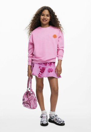 Pink sweatshirt featuring an orange flower design. Paired with a pink floral skirt, silver sandals, and a matching pink handbag.