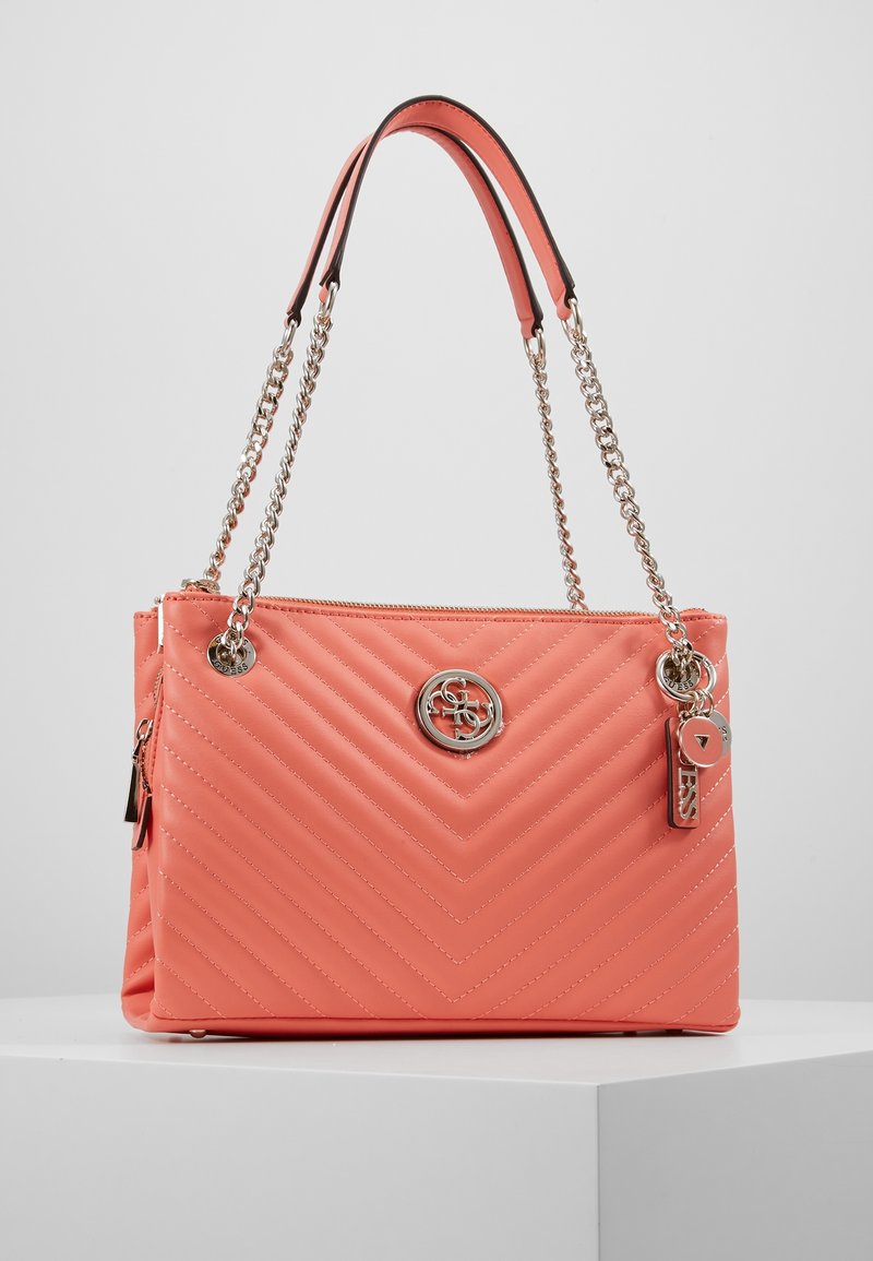 Sac à main matelassé corail avec une bandoulière chaîne noire et argentée. Présente un logo argenté à l'avant et une fermeture éclair avec un pendentif attaché.