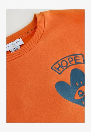 Oranje sweatshirt met geribde halslijn, met een blauwe geborduurde "HOPE" graphic en een hartontwerp. Het label geeft maat en oorsprong aan.